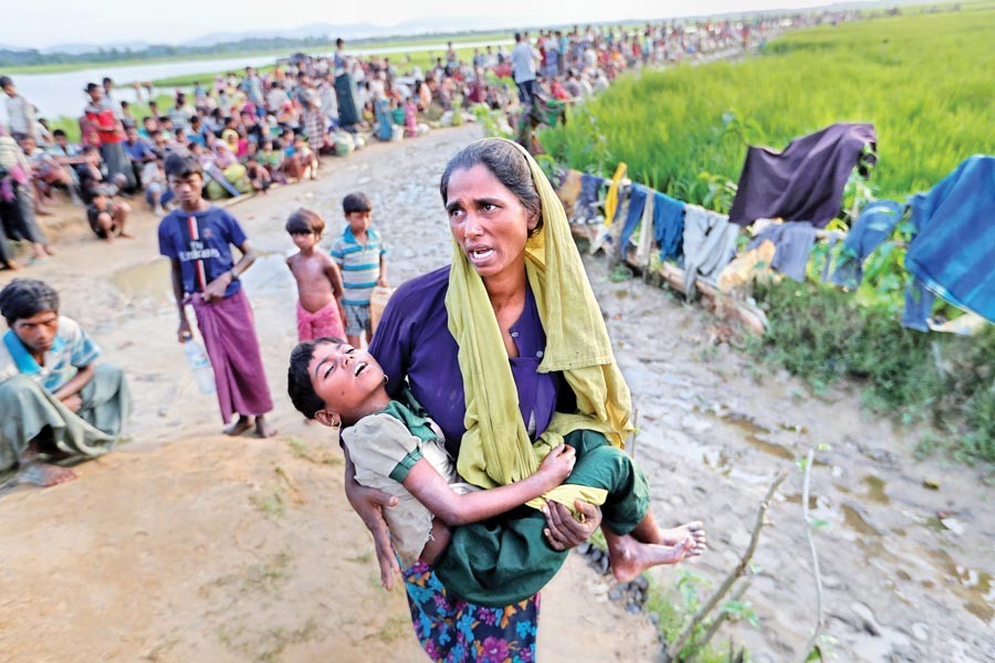 A Rohingya woman carries her daughter while searching for help as she along with other refugees waits for army permission on Tuesday to move to Cox's Bazar's Palang Khali camps after entering Bangladesh. 	— Reuters photo