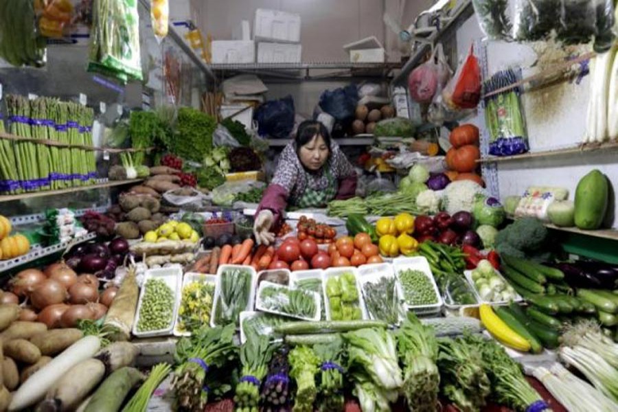 A vendor reaches out for vegetables at her shop in a market in Beijing.                       	—  Reuters