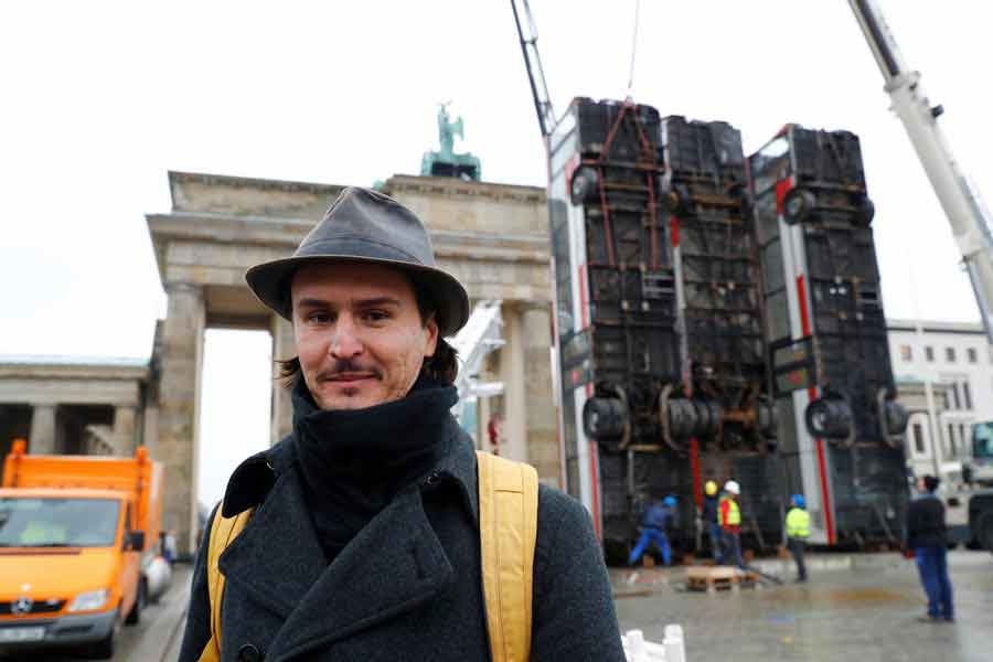 BERLIN: German-Syrian artist Manaf Halbouni poses in front of his installation "Monument" in front of the Brandenburg Gate in Berlin on Friday.  — Reuters