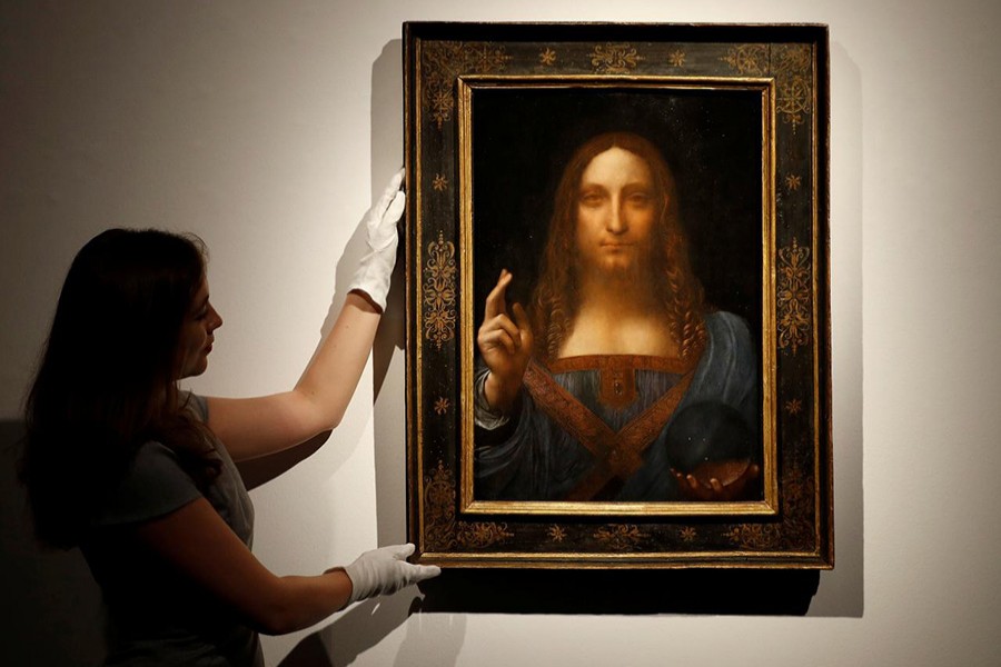 Members of Christie's staff pose for pictures next to Leonardo da Vinci's "Salvator Mundi" painting. - Reuters file photo