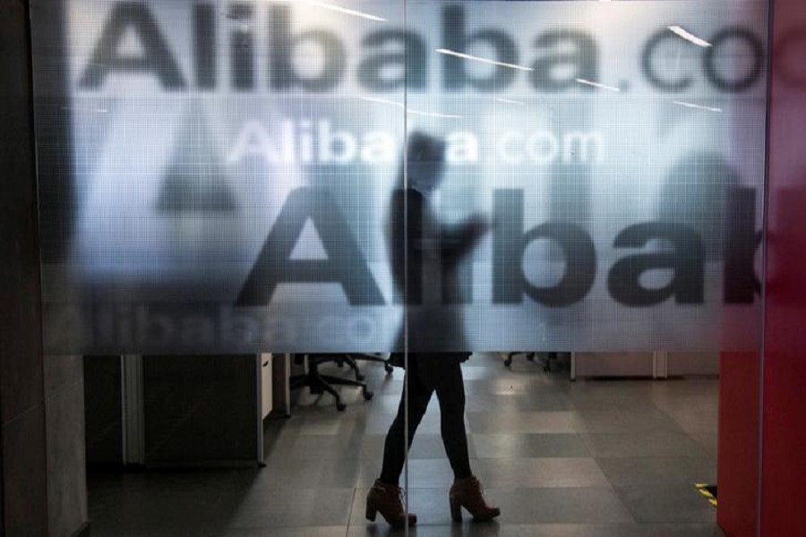 An employee is seen behind a glass wall with the logo of Alibaba at the company's headquarters on the outskirts of Hangzhou, Zhejiang province, April 23, 2014. Reuters/File Photo