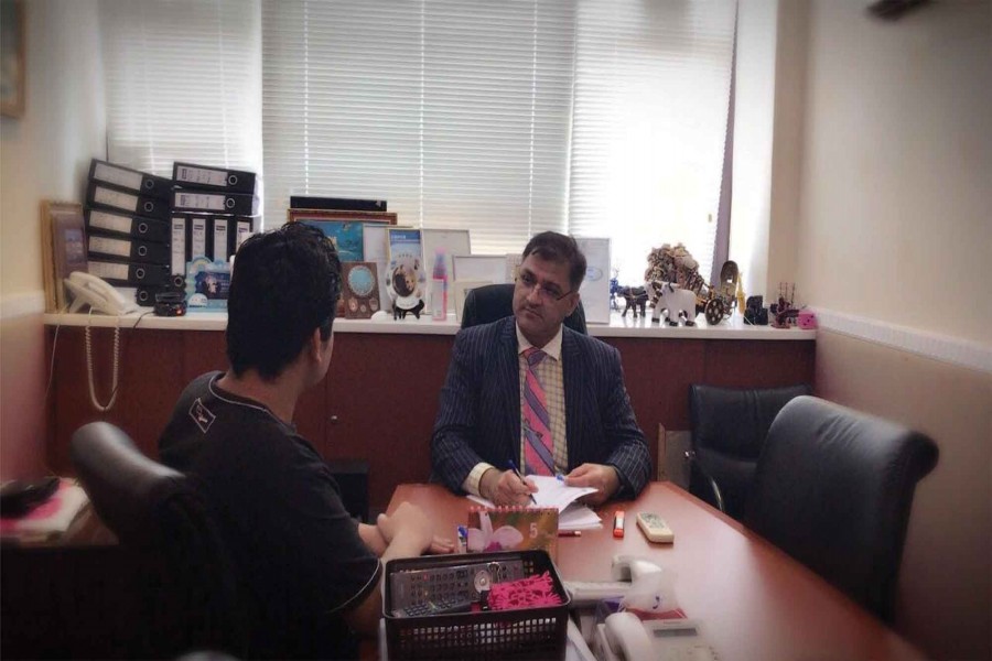 Immigration consultant Richard Aziz Butt (right) talking to a client in his office