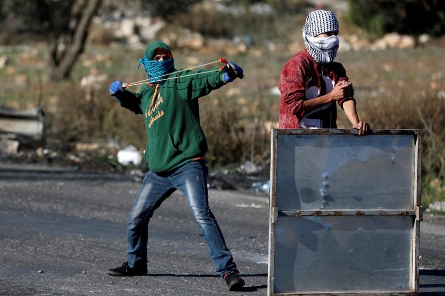 A Palestinian protester is seen using a sling shot to hurl stones towards Israeli troops near the Jewish settlement of Beit El, near the West Bank city of Ramallah. Reuters