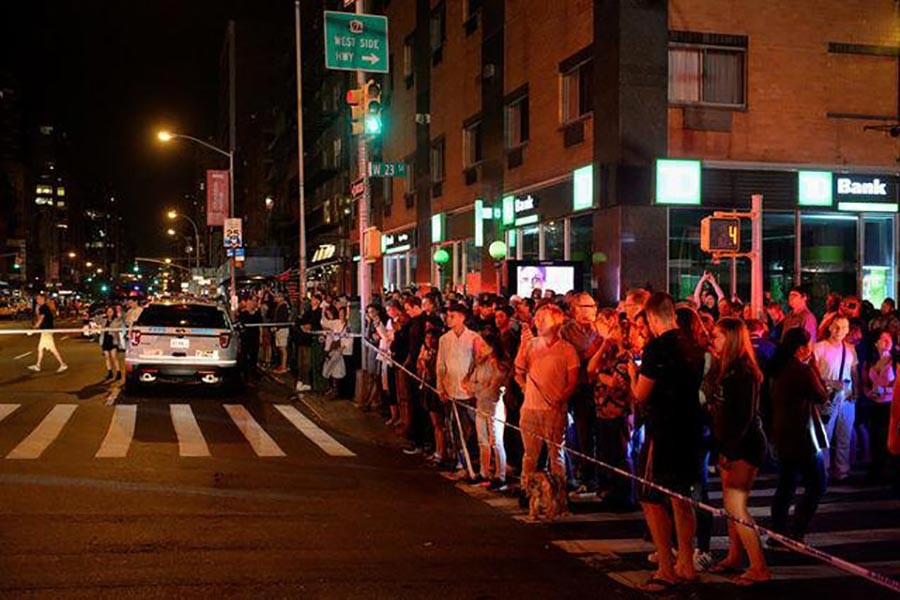 Onlookers stand behind a police cordon near the site of an explosion in the Chelsea neighborhood of Manhattan of New York on Monday. -Reuters