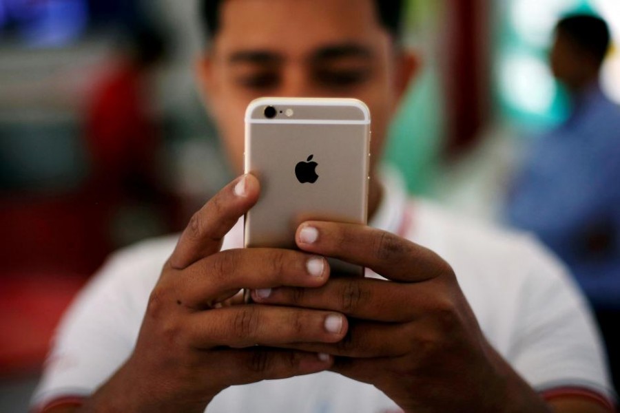 A salesman checks a customer's iPhone at a mobile phone store in New Delhi, India, July 27, 2016. -