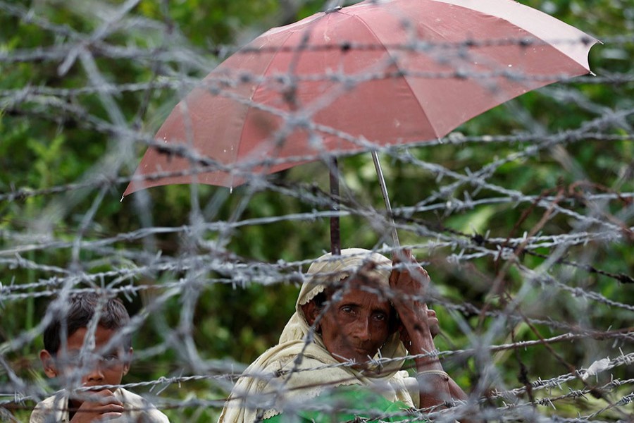 A Rohingya refugee woman and boy look on through barbed wire as they wait for boat to cross the border through Naf river in Maungdaw, Myanmar on September 7 last. - Reuters file photo