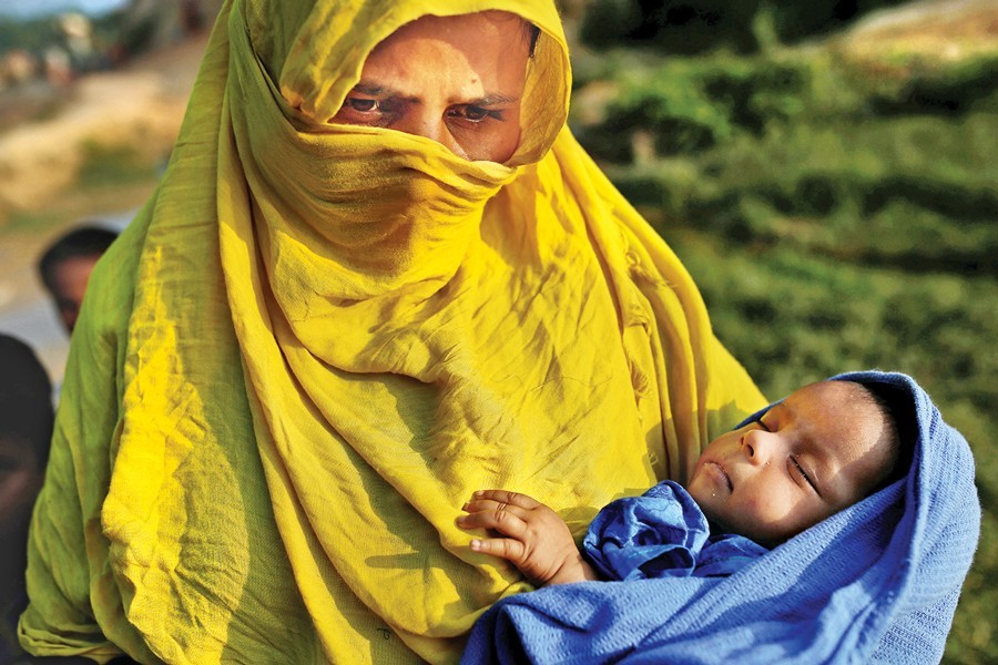 A Rohingya woman holds her 20-days-old girl at the Jamtoli refugee camp near Cox’s Bazar on Friday. — Reuters