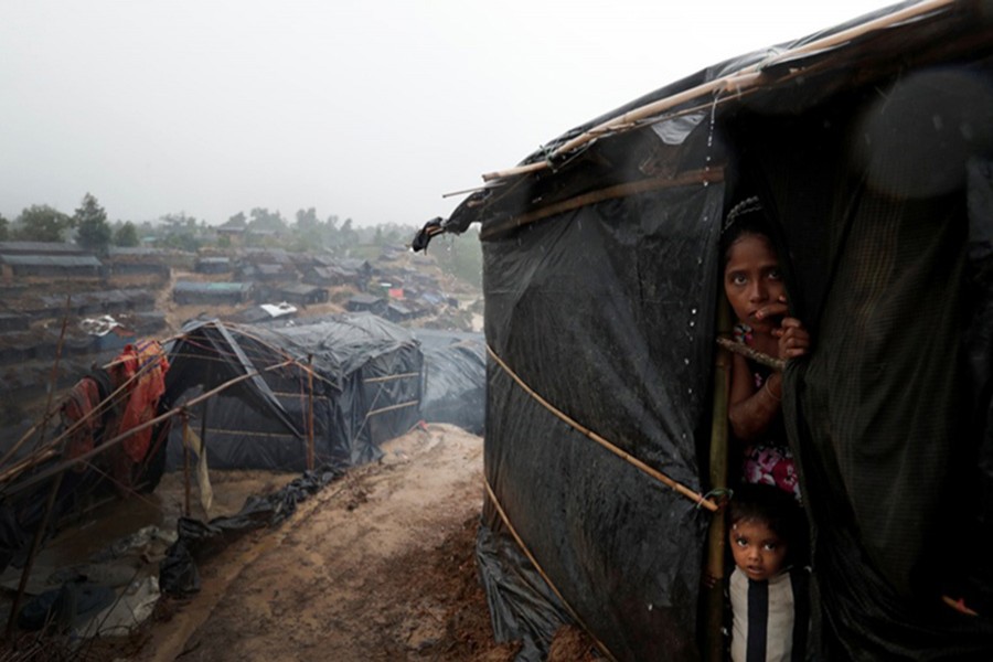 A Rohingya refugee woman and boy look on through barbed wire as they wait for boat to cross the border through Naf river in Maungdaw, Myanmar on September 7 last. - Reuters file photo