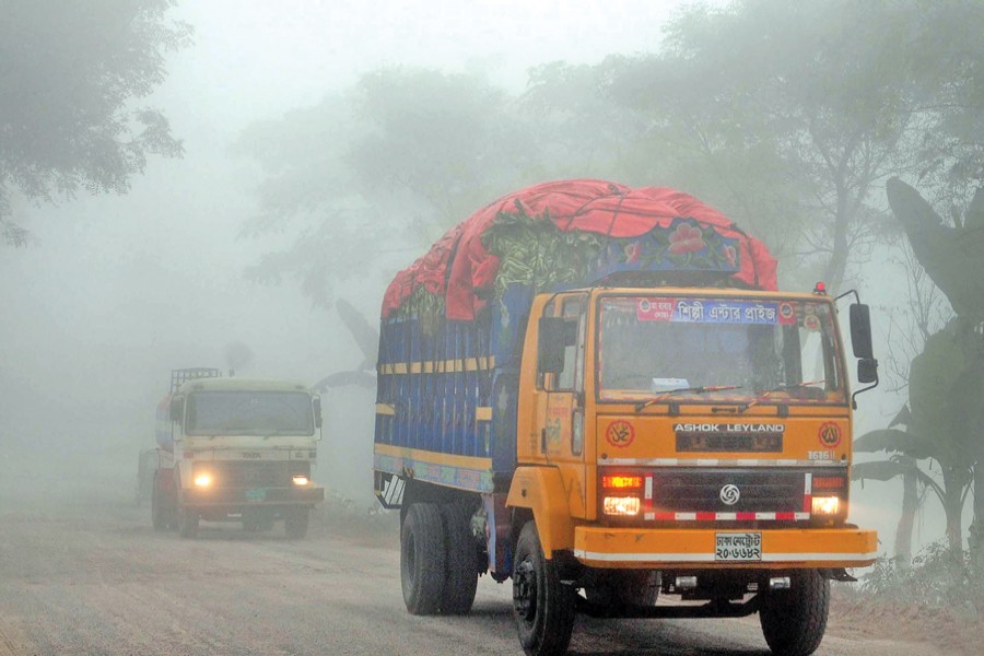 Vehicles ply a highway amid a thick blanket of fog in Bogra on Friday. The entire country is now experiencing a chilly weather with the mercury going down gradually. 	— Focus Bangla