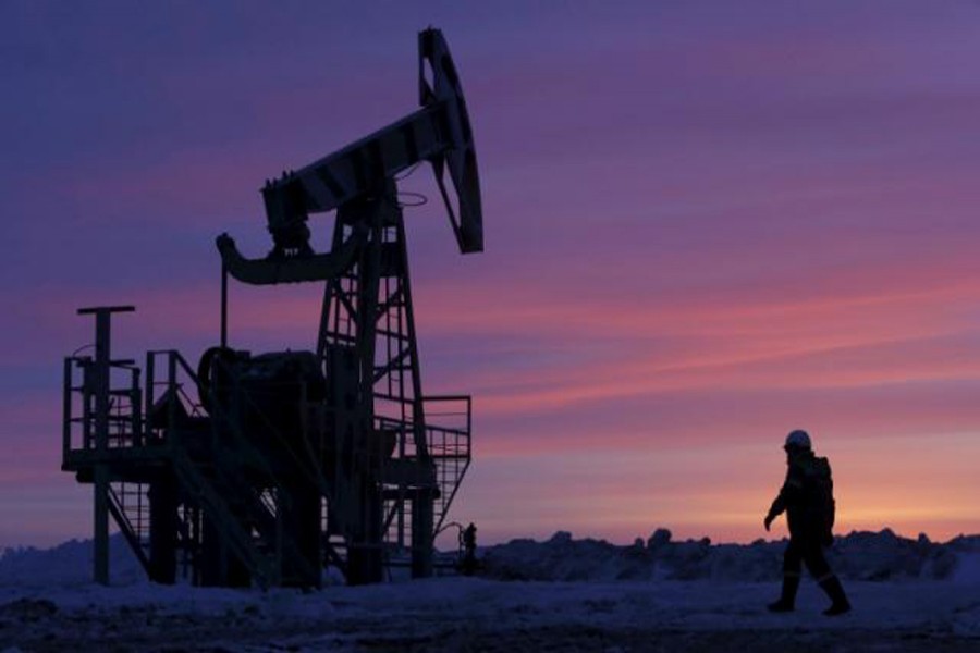 A worker walks past a pump jack on an oil field owned by Bashneft in Bashkortostan, Russia.	— Reuters