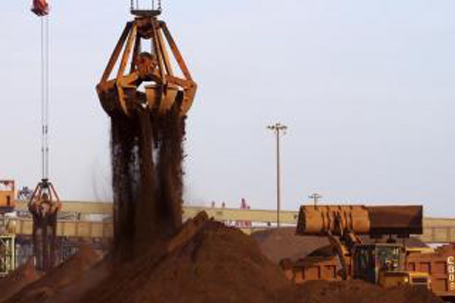 Cranes unload imported iron ore from a ship at a port in Rizhao, Shandong province, China. 	— Reuters