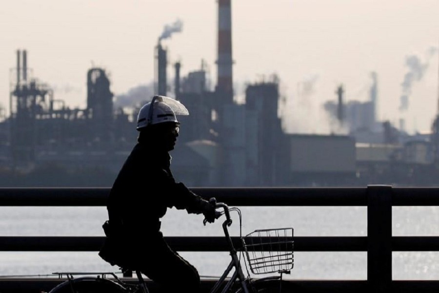 A worker cycles near a factory at the Keihin industrial zone in Kawasaki, Japan, November 15, 2017. Reuters/File Photo