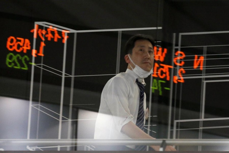 A visitor is seen as market prices are reflected in a glass window at the Tokyo Stock Exchange (TSE) in Tokyo, Japan, February 6, 2018. Reuters