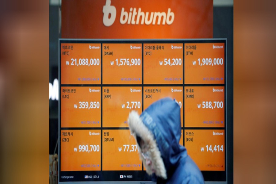 A man walks past an electric board showing exchange rates of various cryptocurrencies at Bithumb cryptocurrencies exchange in Seoul, South Korea, January 11, 2018.Reuters.