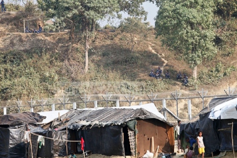 Myanmar border force troops (in blue uniform) seen near the border fence at Tambru border in Bandarban on Thursday