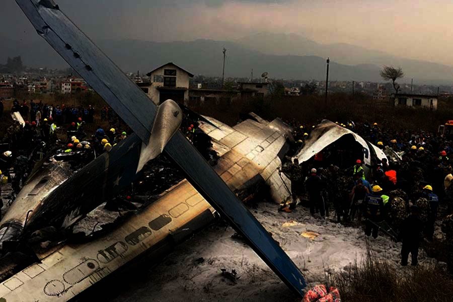 Nepalese rescuers stand near a passenger plane from Bangladesh that crashed at the airport in Kathmandu of Nepal on Monday. -AP Photo