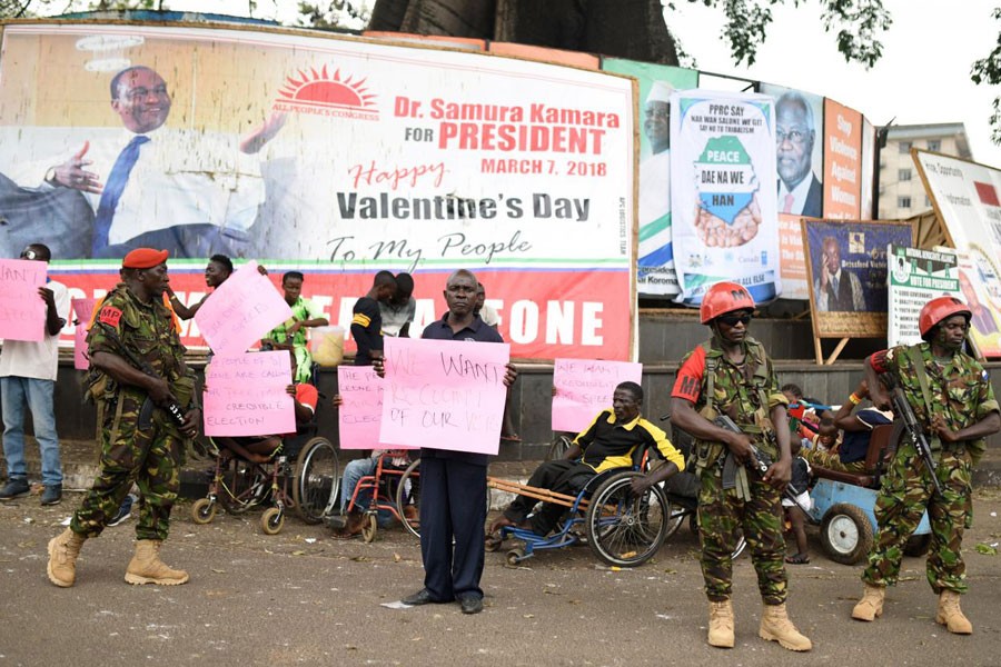 People hold signs asking for a re-count and credible elections near the high court in Freetown, Sierra Leone March 26, 2018. Reuters.