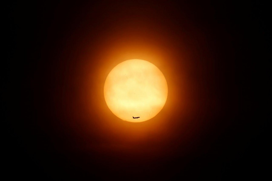 A passenger jet flies past the setting sun in Shanghai March 11, 2014. Reuters/File Photo