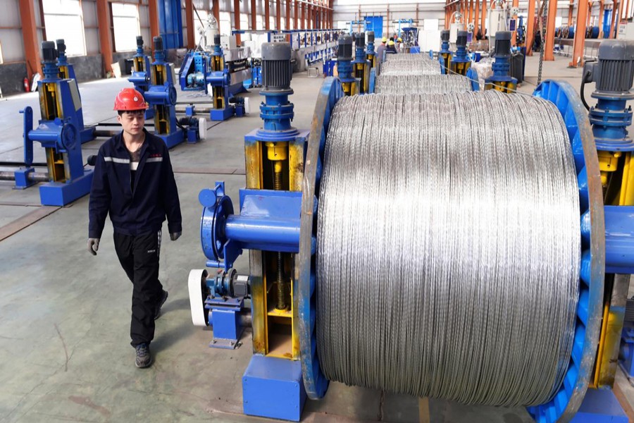 A worker walking past aluminium wires at a plant inside an industrial park in Binzhou, Shandong province, China                                	— Reuters