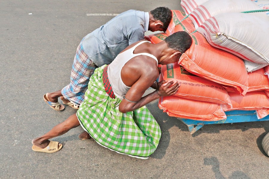 Two day-labourers pushing a goods-laden cart on a road at Dayaganj in Dhaka city on Monday, ahead of May Day  today (Tuesday) — FE Photo by Shafiqul Alam