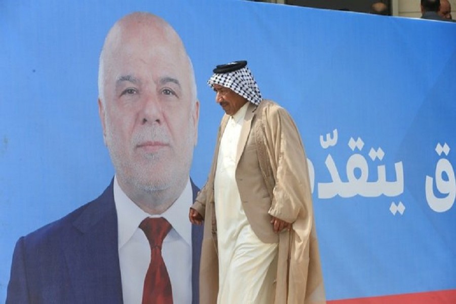 A man walks past a campaign poster of Iraqi Prime Minister Haidar al-Abadi ahead of the parliamentary election, in Najaf, Iraq May 3, 2018. Reuters/Files