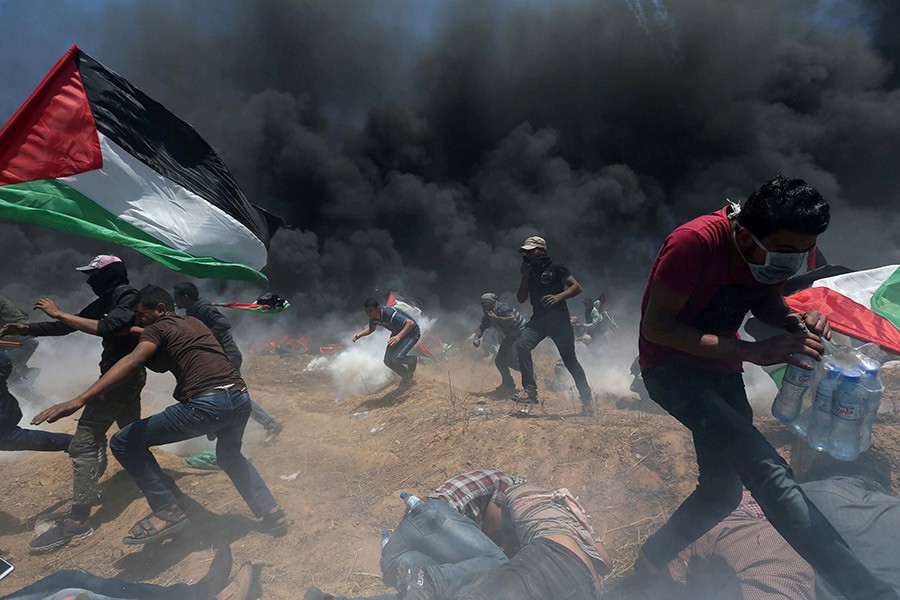 Palestinian demonstrators running for cover from Israeli fire and tear gas during a protest against US embassy move to Jerusalem at the Israel-Gaza border in the southern Gaza Strip on Monday - Reuters photo