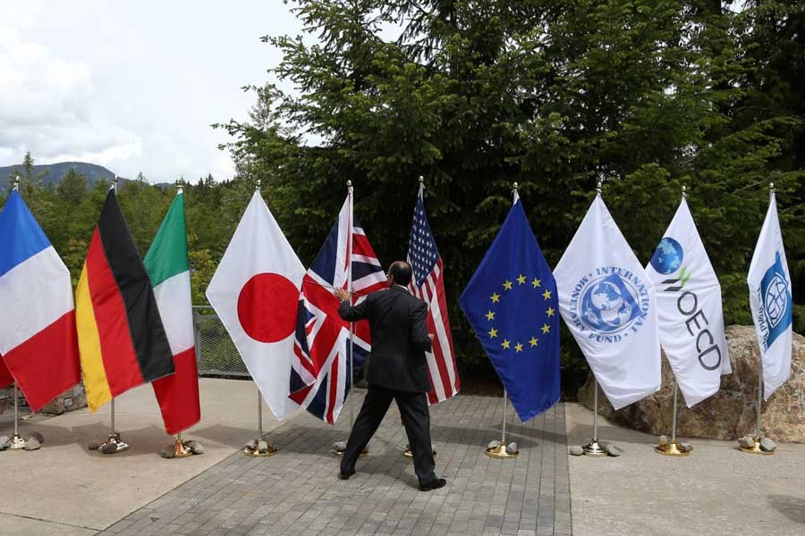 A delegate grabs a flag to prevent it from being blown over by the wind outside of the G7 Finance Ministers summit in Whistler, British Columbia, Canada, May 31, 2018. Reuters