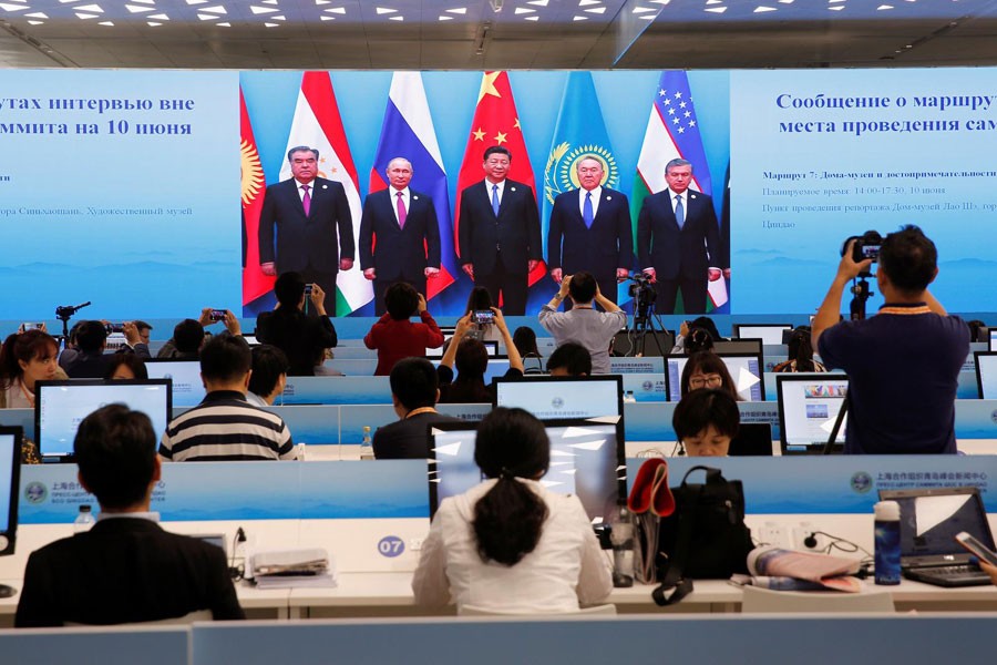 A TV screen shows a live broadcast of Chinese President Xi Jinping attending a group photo of Shanghai Cooperation Organization (SCO) summit at the media center, in Qingdao, Shandong Province, China, June 10, 2018. Reuters