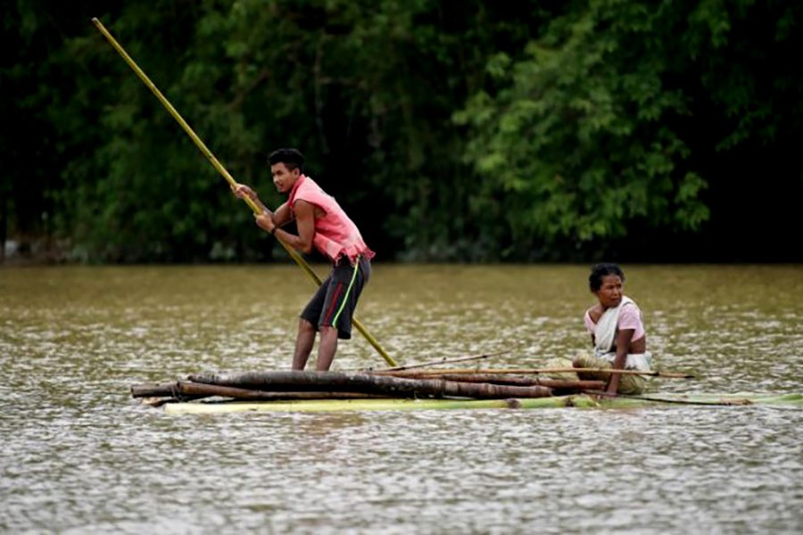 Villagers using a makeshift raft to cross a flooded area in Assam of India. The photo was taken on Monday. -Reuters Photo