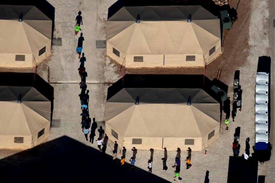 Immigrant children are led by staff in single file between tents at a detention facility next to the Mexican border in Tornillo of Texas in US recently. -Reuters Photo