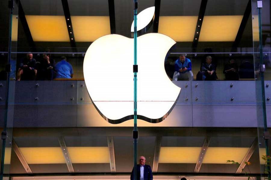 A customer stands underneath an illuminated Apple logo as he looks out the window of the Apple store located in central Sydney, Australia, May 28, 2018. Reuters/Files