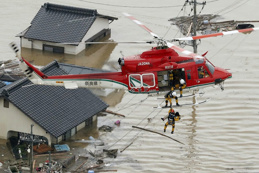 An aerial view shows a local resident being rescued from a submerged house by rescue workers using helicopter at a flooded area in Kurashiki, southern Japan, in this photo taken by Kyodo on Saturday. Kyodo photo via Reuters