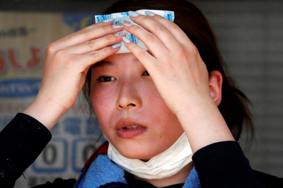 A volunteer, for recovery work, uses a pack of refrigerant to a cool down as she takes a break in a heat wave at a flood affected area in Kurashiki, Okayama Prefecture, Japan, July 14, 2018 - Reuters file photo