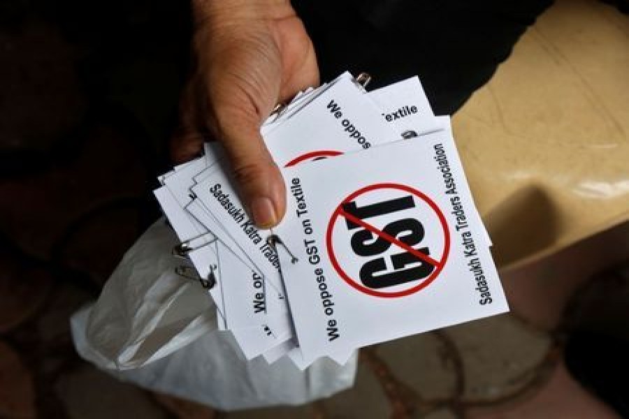 A cloth merchant holds message papers to distribute as he attends a procession during a strike to protest the implementation of the Goods and Services Tax (GST) on textiles in Kolkata, India, June 30, 2017. Reuters/File Photo