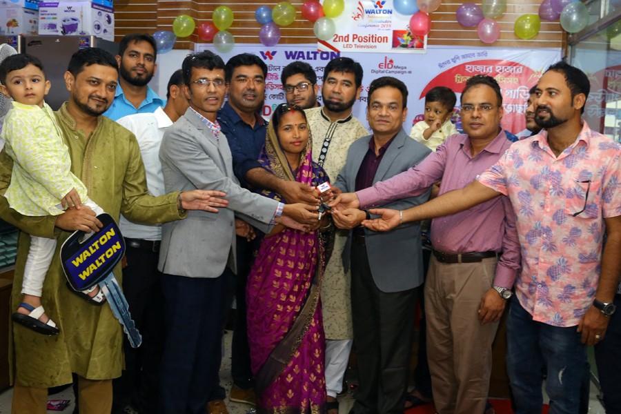 Md Humayun Kabir, executive director of Walton, and Md Rayhan, deputy executive director of Walton Group, handing over the key of a brand new car to Shima Shill at a Walton outlet in Chattogram on Tuesday   