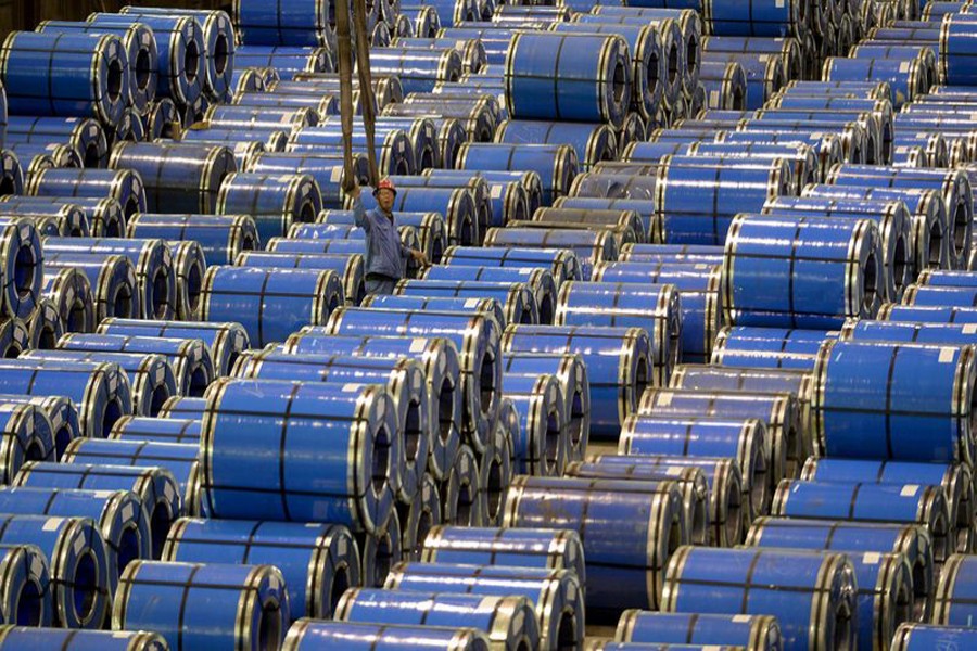 An employee working amid stainless steel sheets at a steel factory in Taiyuan, Shanxi province, China  	— Reuters