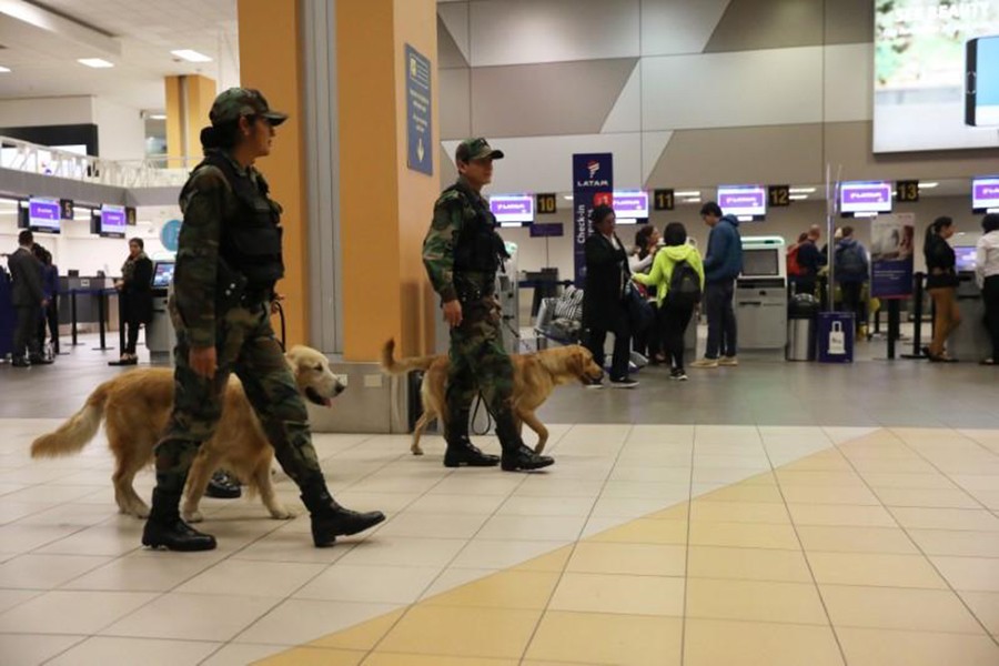 Police patrol with dogs near the LATAM airlines gates in Jorge Chavez airport in Callao, Peru on Thursday — Reuters