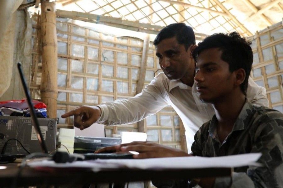 Mohib Bullah, a member of Arakan Rohingya Society for Peace and Human Rights, helps a boy during data entry on a laptop given by Human Rights Watch in Cox's Bazar, Bangladesh on April 21 last — Reuters