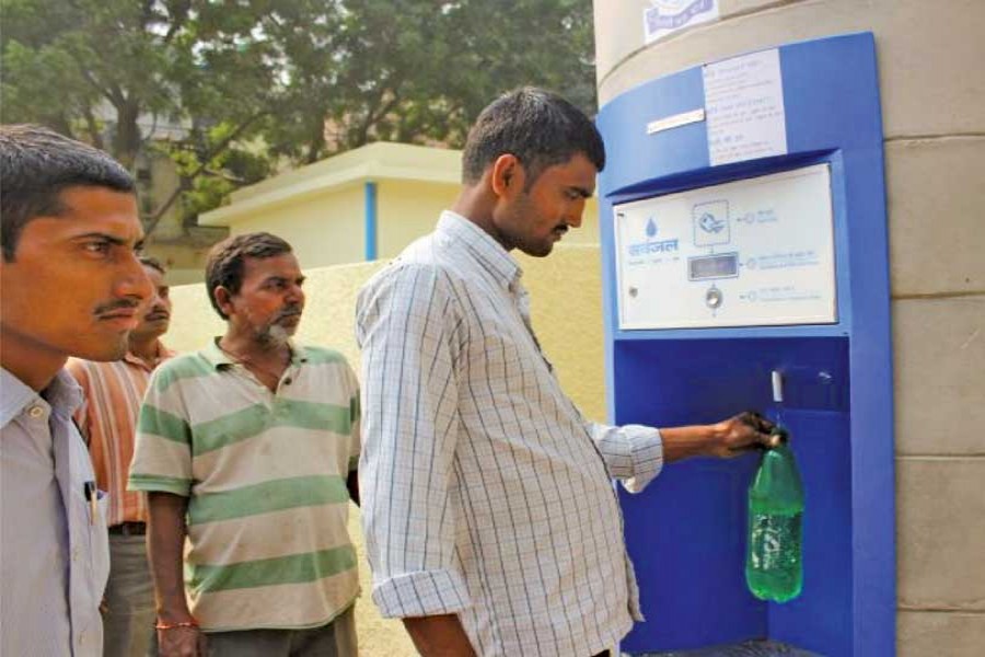 A man draws water from a solar-powered water ATM in New Delhi's Savda Ghevra slum settlement. Thanks to these machines, which allow users to withdraw water with a rechargeable card, waterborne diseases have become less frequent here.      —Photo credit: Ranjit Devraj/IPS