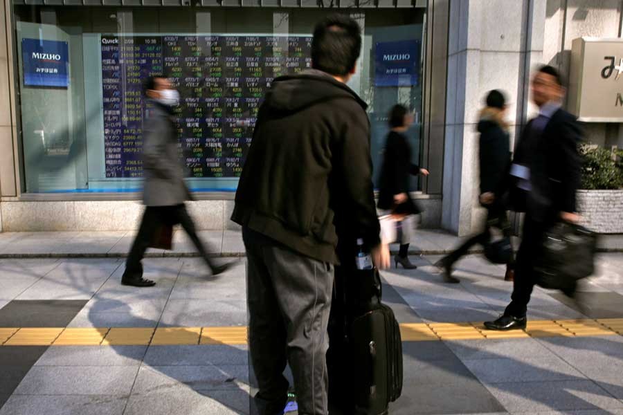 A man looks at an electronic stock quotation board outside a brokerage in Tokyo, Japan February 9, 2018. Reuters/Files