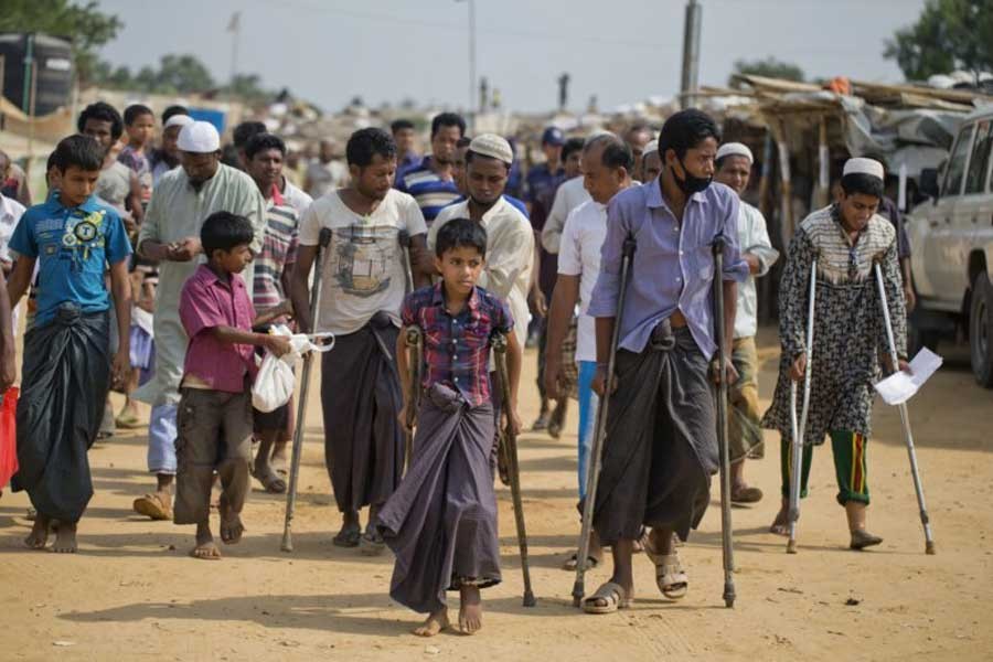 In this April 29, 2018 file photo, wounded Rohingya refugees walk with the help of crutches as they await the arrival of a UN Security Council team at the Kutupalong Rohingya refugee camp in Ukhia upazila, Cox's Bazar.