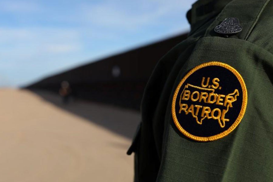 A US border patrol agent walks along the border fence between Mexico and the United States near Calexico, California, US February 8, 2017 – Reuters