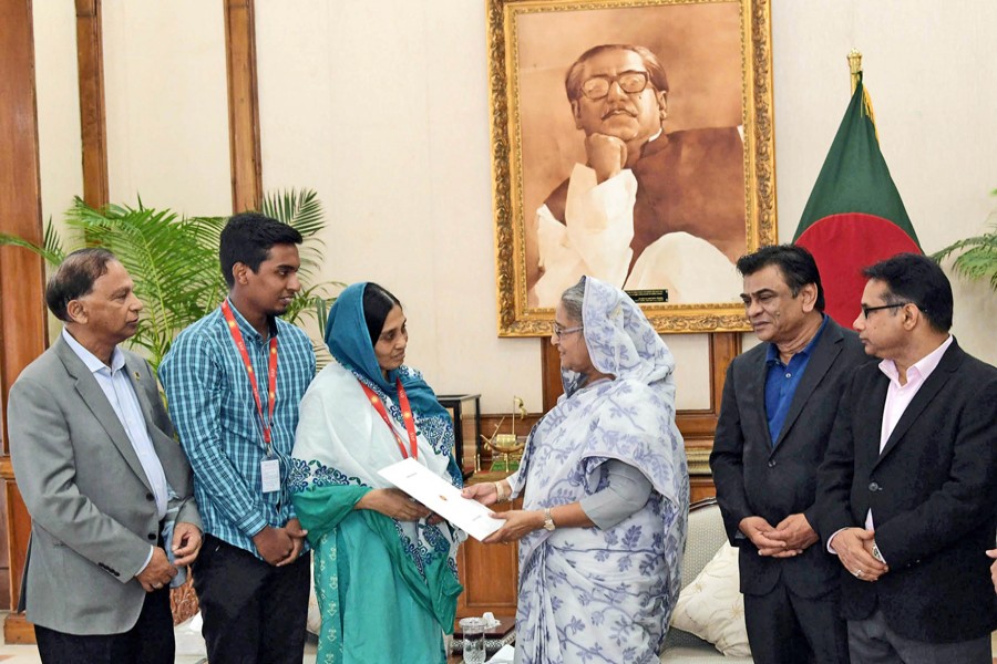 Prime Minister Sheikh Hasina handing over the papers of residential flats to the families of two former national footballers and a hockey player at a function held at the Prime Minister's official residence Ganobhaban in the city on Thursday 	— PID