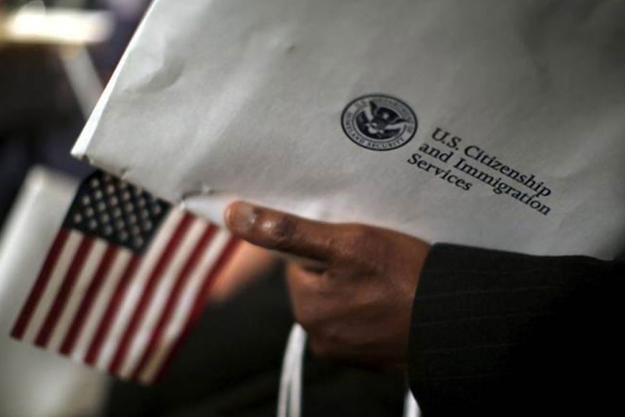 A man holds an envelope from the US Citizenship and Immigrations Service during a naturalisation ceremony at the National Archives Museum in Washington December 15, 2015 – Reuters