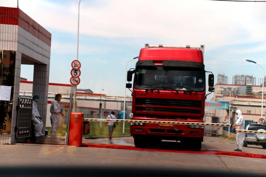 Workers in protective suits are seen by a truck at a plant of pork processor in Zhengzhou, Henan August 17, 2018. Reuters photo