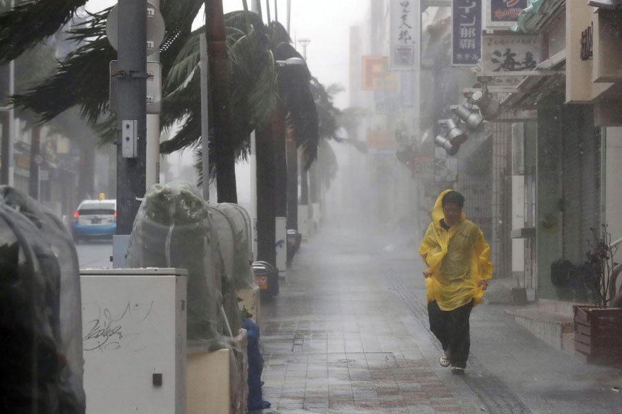 A passer-by walks in heavy rain and wind caused by Typhoon Trami in the prefectural capital Naha, on the southern island of Okinawa, in this photo taken by Kyodo, September 29, 2018 - Mandatory credit Kyodo/via Reuters