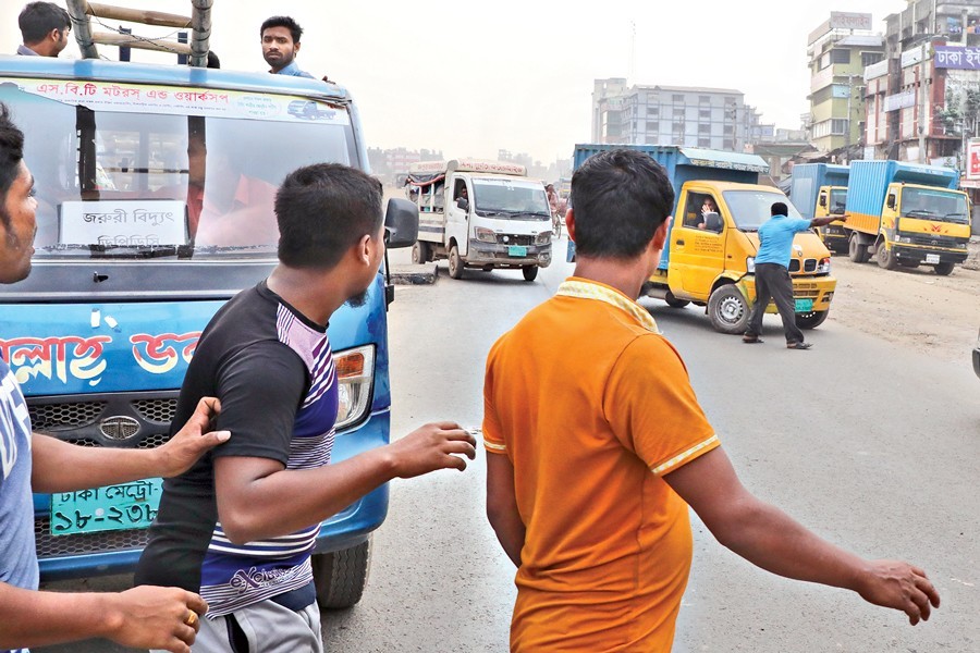 Transport workers preventing trucks and covered vans from plying at West Dolairpar in the city on Monday during the ongoing indefinite strike called by the Bangladesh Goods Transport Owners Workers United Association demanding amendment to the Road Transport Act 2018 — FE photo