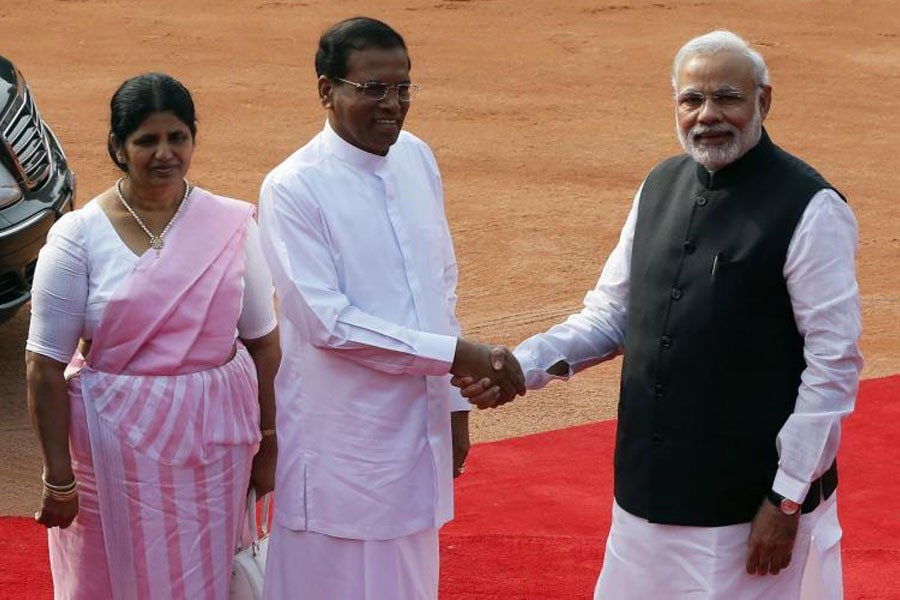 Sri Lanka's President Mithripala Sirisena (C) shakes hands with Indian Prime Minister Narendra Modi (R) as his wife Jayanthi Sirisena looks on during Sirisena's ceremonial reception at the forecourt of India's Rashtrapati Bhavan presidential palace in New Delhi February 16, 2015 - Reuters