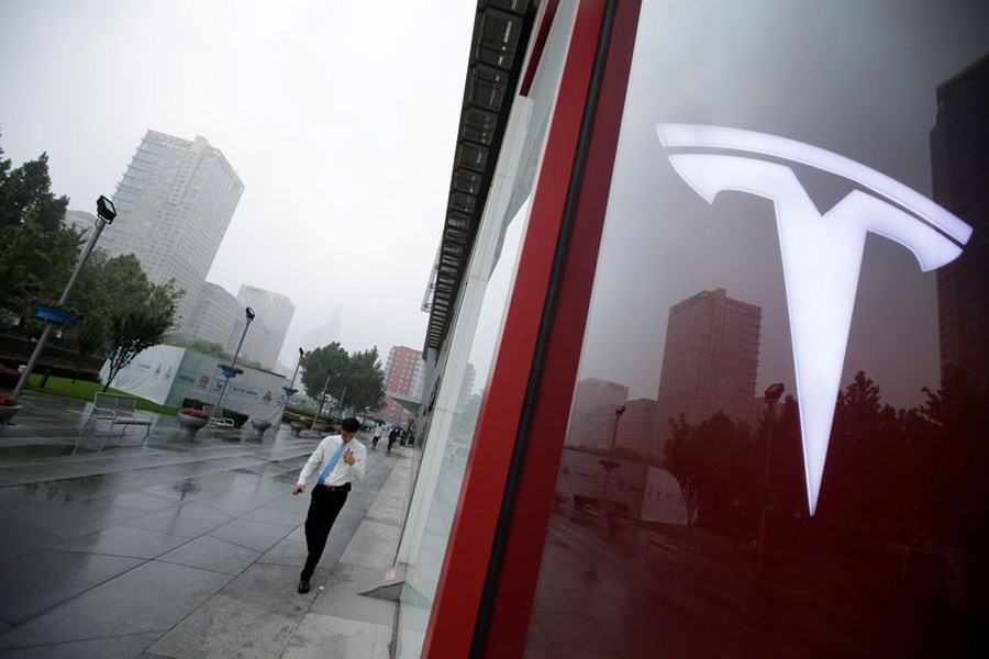 A man walks near a logo of Tesla outside its China headquarters at China Central Mall in Beijing, China, July 11, 2018. Reuters/File Photo