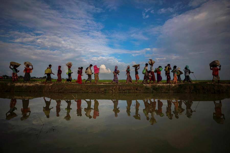 Rohingya refugees are reflected in rain water along an embankment next to paddy fields after fleeing from Myanmar into Palang Khali, near Cox's Bazar, Bangladesh, November 2, 2017. Reuters/Files